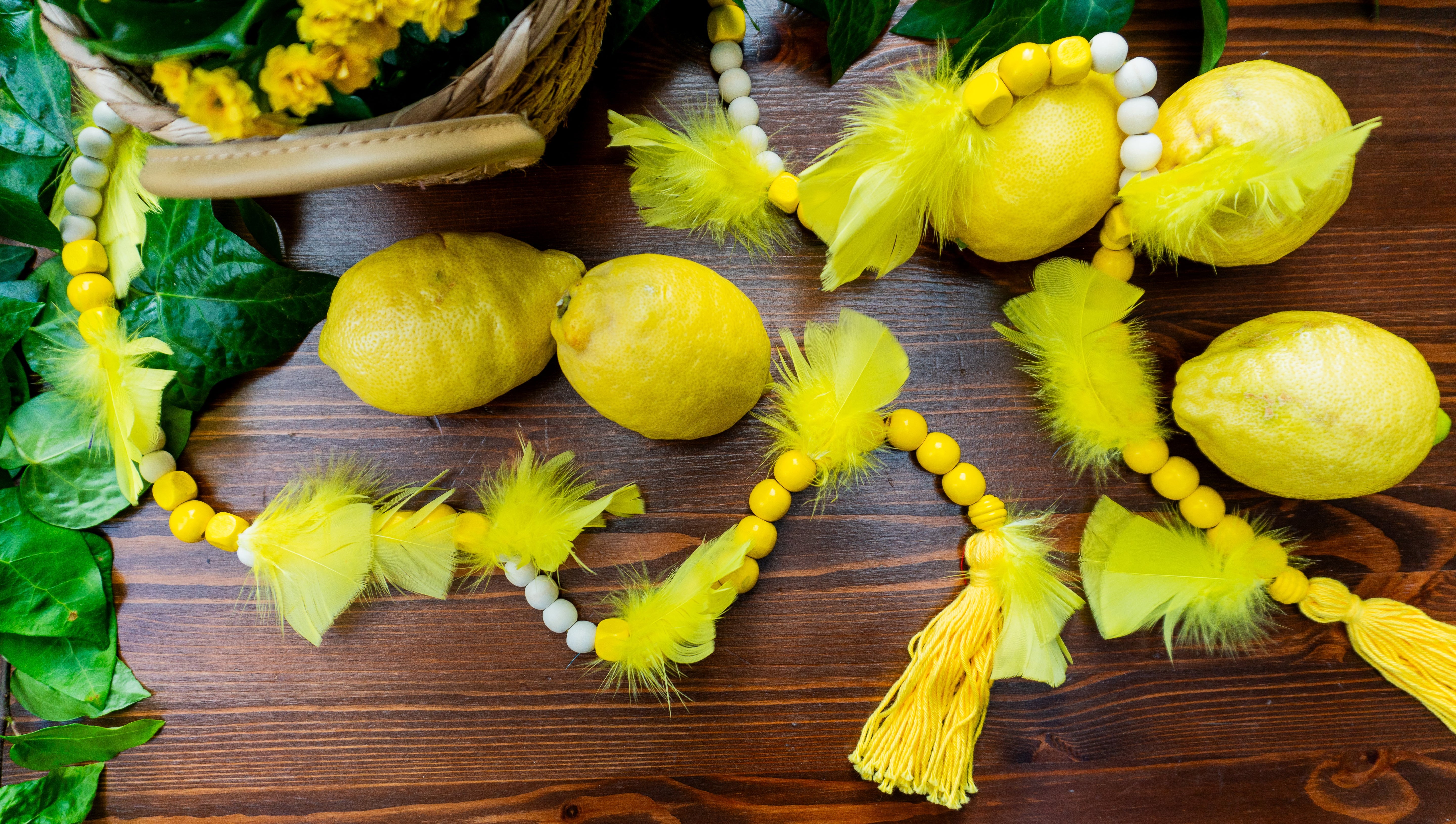 Holzperlen Kette in Zitronengelb für die angesagte Zitronen Dekoration. Mit Federn und Quasten verziert. Passend zu unserem Zitronen-Häkel Platzset.