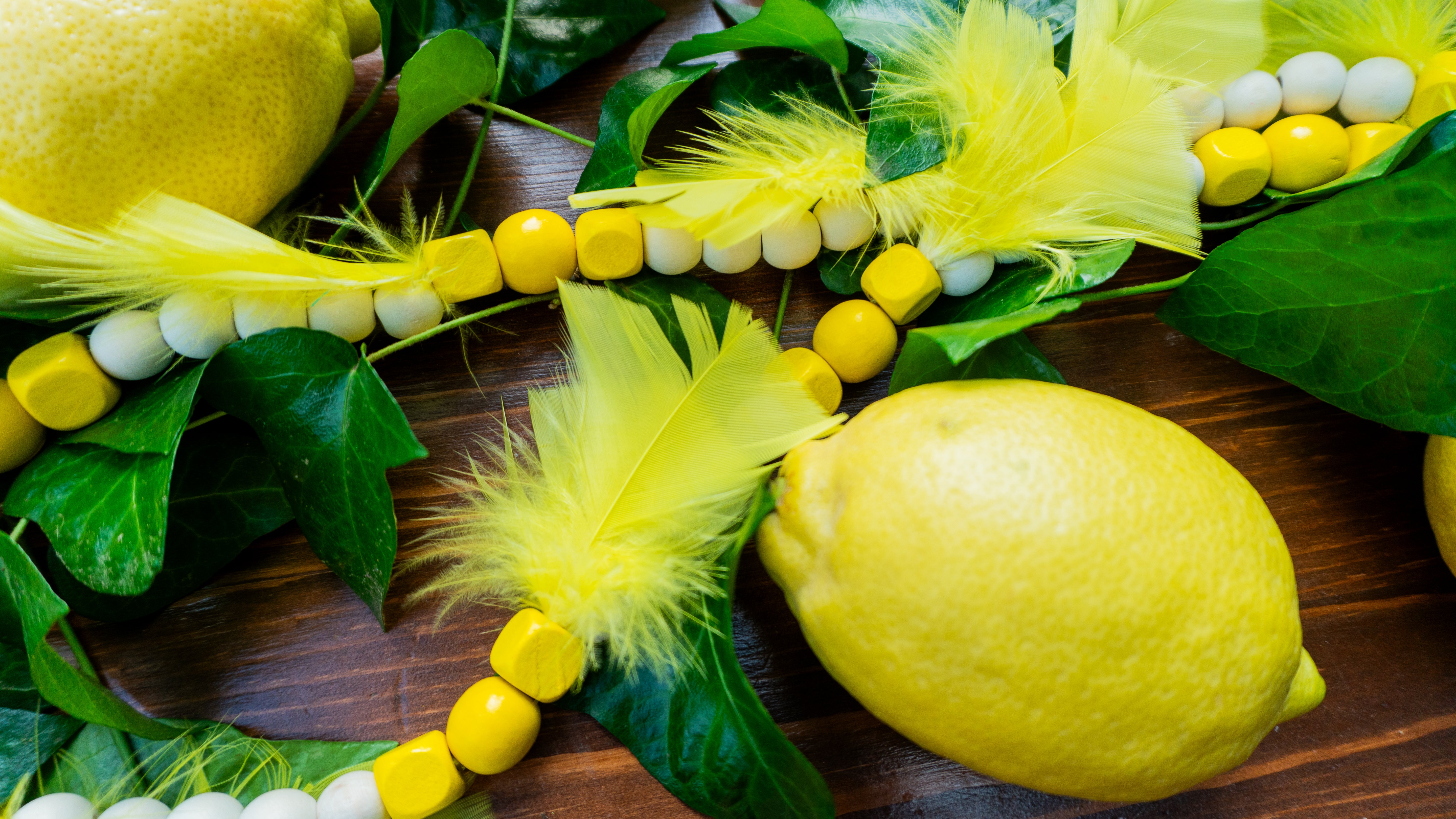 Holzperlen Kette in Zitronengelb für die angesagte Zitronen Dekoration. Mit Federn und Quasten verziert. Passend zu unserem Zitronen-Häkel Platzset.