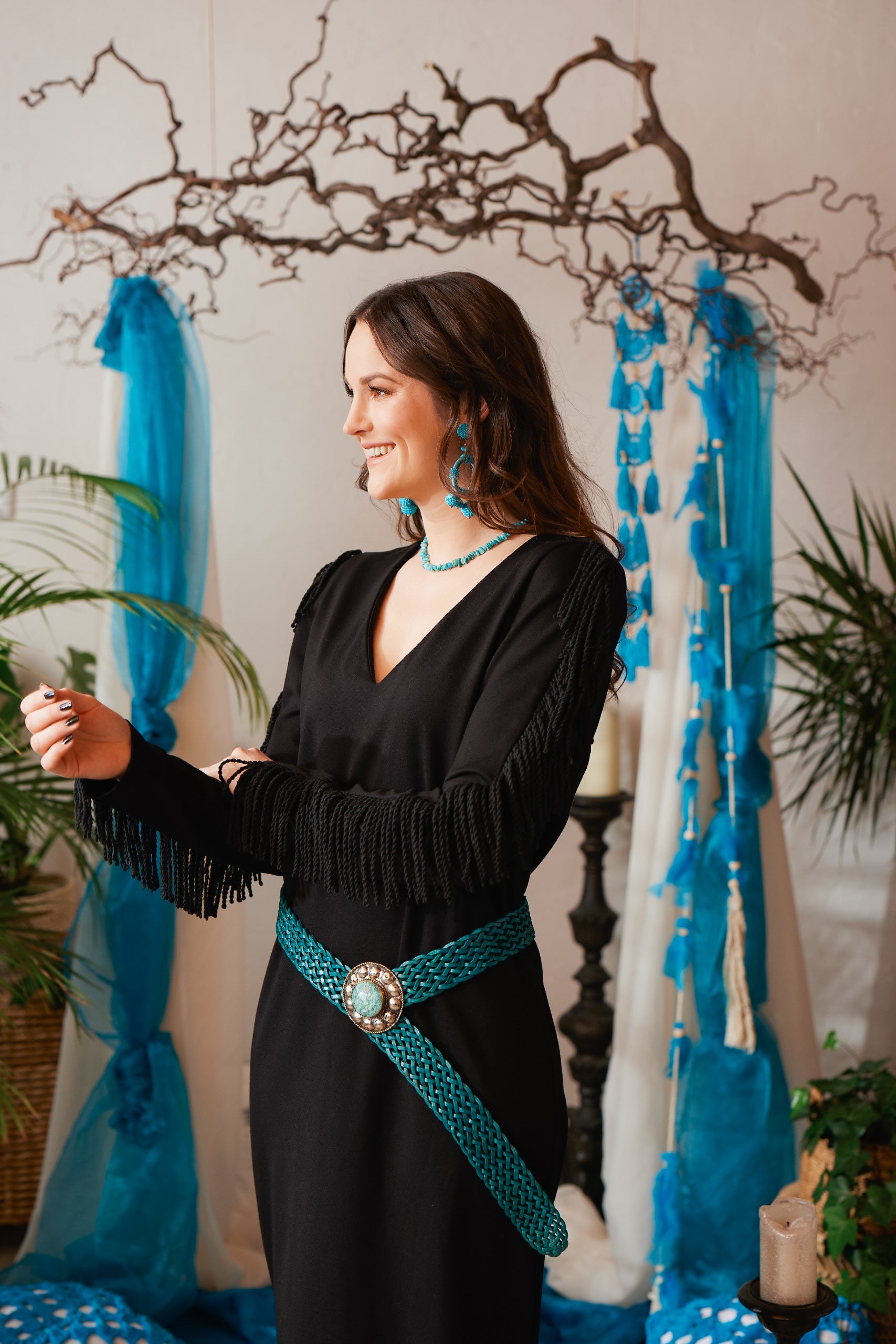 Dieses lange, schwarze Boho-Stretchkleid überzeugt mit gedrehten Fransen an den Ärmeln und einem eleganten V-Ausschnitt. Schulterpolster und seitliche Schlitze verleihen dem Kleid eine moderne Silhouette. Das blickdichte, formbeständige Stretchmaterial sorgt für hohen Tragekomfort und eine entspannte Passform. Vielseitig kombinierbar, lässt es sich mit einem Gürtel individuell stylen – ideal für einen lässigen Bohemian Look. Das streng limitierte Design macht es zu einem besonderen Highlight