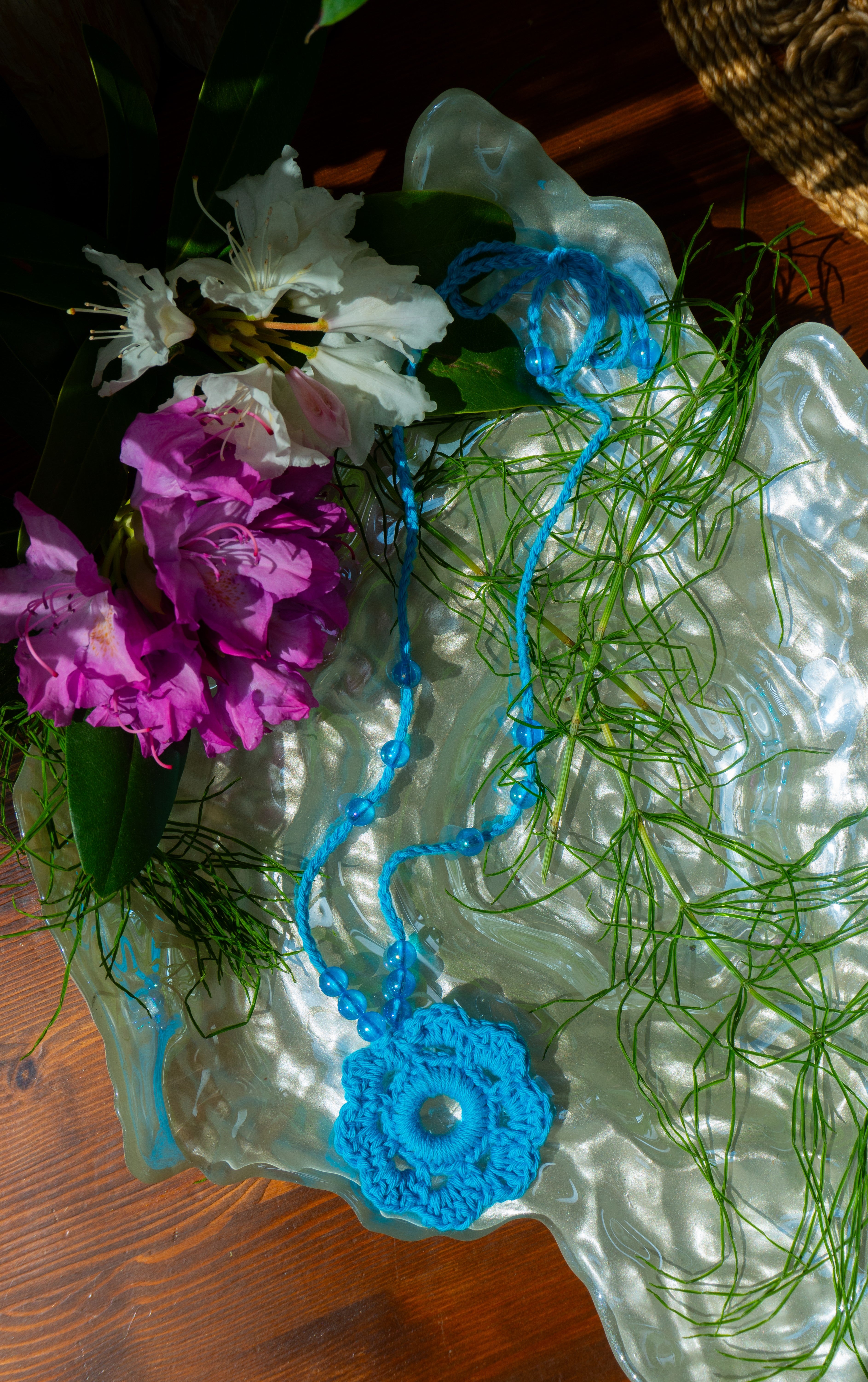 Verspieltes Design und sommerliche Farben - unsere handgefertigte Häkelkette in Türkis mit Blumenanhänger und passenden Perlen verleiht deinem Outfit einen Hauch von Individualität und ist das perfekte Boho Accessoire für den Sommerlook! Entdecke einzigartige und stylische Möglichkeiten, um dein Outfit zu stylen.