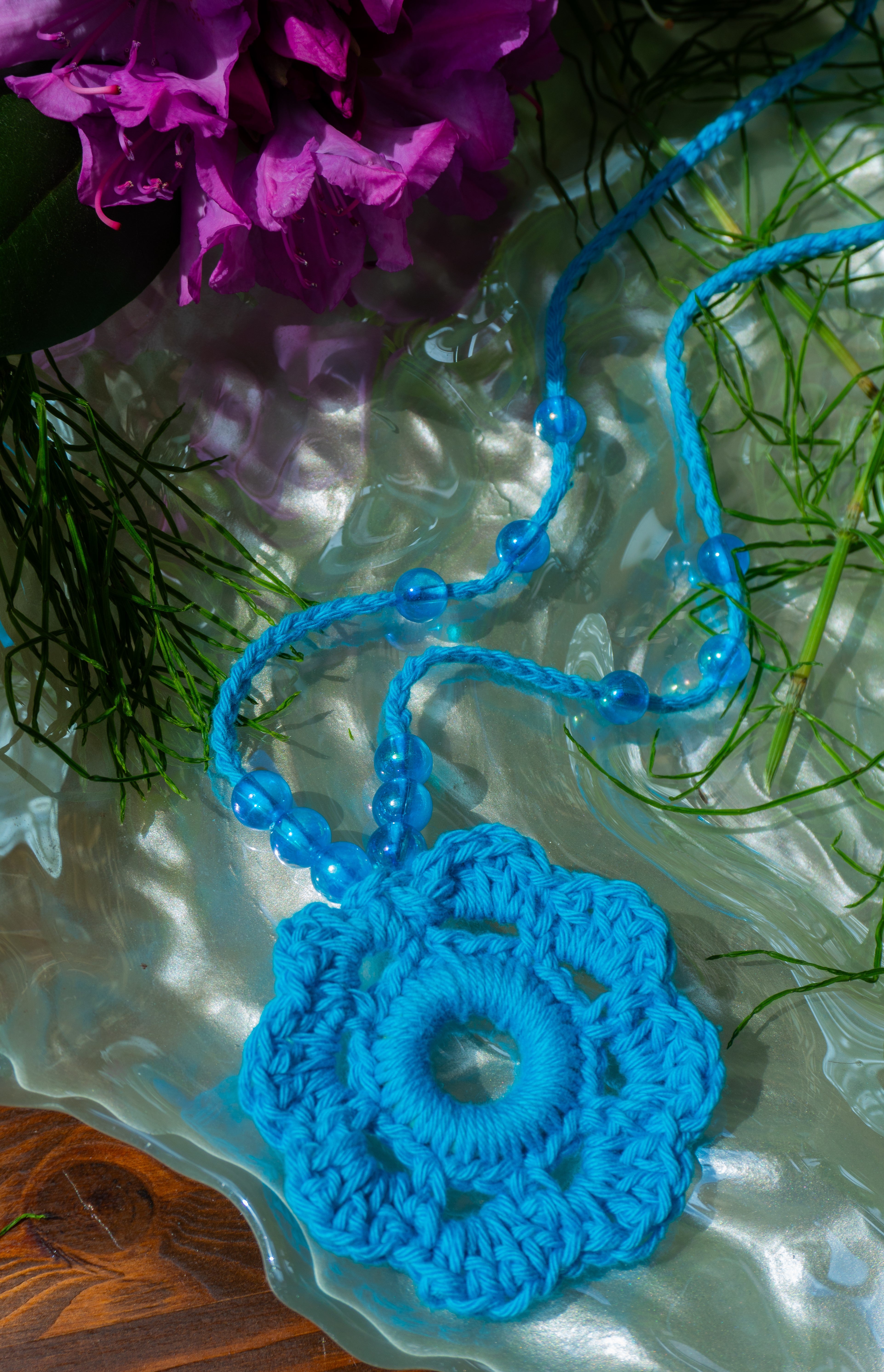 Verspieltes Design und sommerliche Farben - unsere handgefertigte Häkelkette in Türkis mit Blumenanhänger und passenden Perlen verleiht deinem Outfit einen Hauch von Individualität und ist das perfekte Boho Accessoire für den Sommerlook! Entdecke einzigartige und stylische Möglichkeiten, um dein Outfit zu stylen.