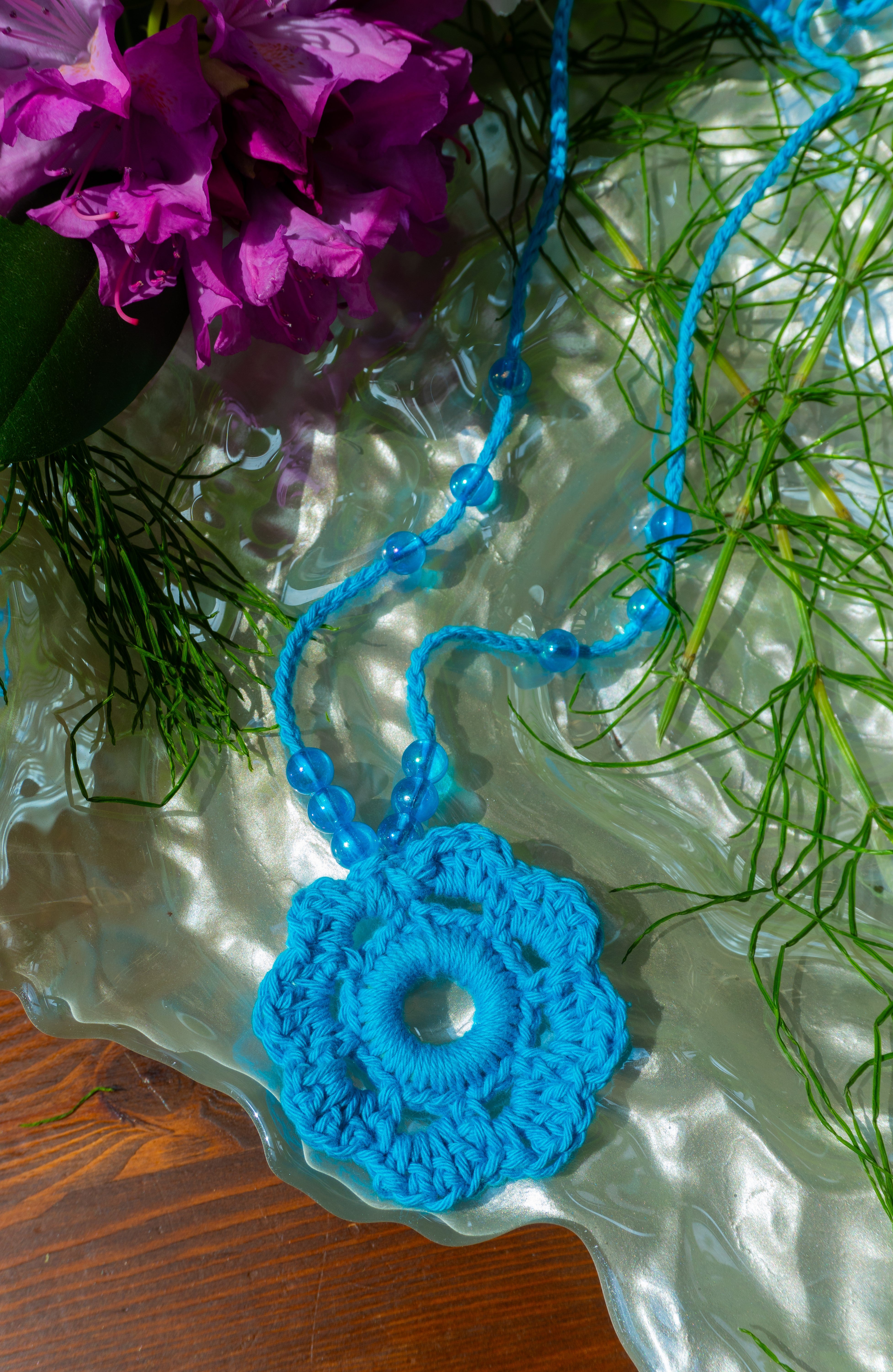 Verspieltes Design und sommerliche Farben - unsere handgefertigte Häkelkette in Türkis mit Blumenanhänger und passenden Perlen verleiht deinem Outfit einen Hauch von Individualität und ist das perfekte Boho Accessoire für den Sommerlook! Entdecke einzigartige und stylische Möglichkeiten, um dein Outfit zu stylen.