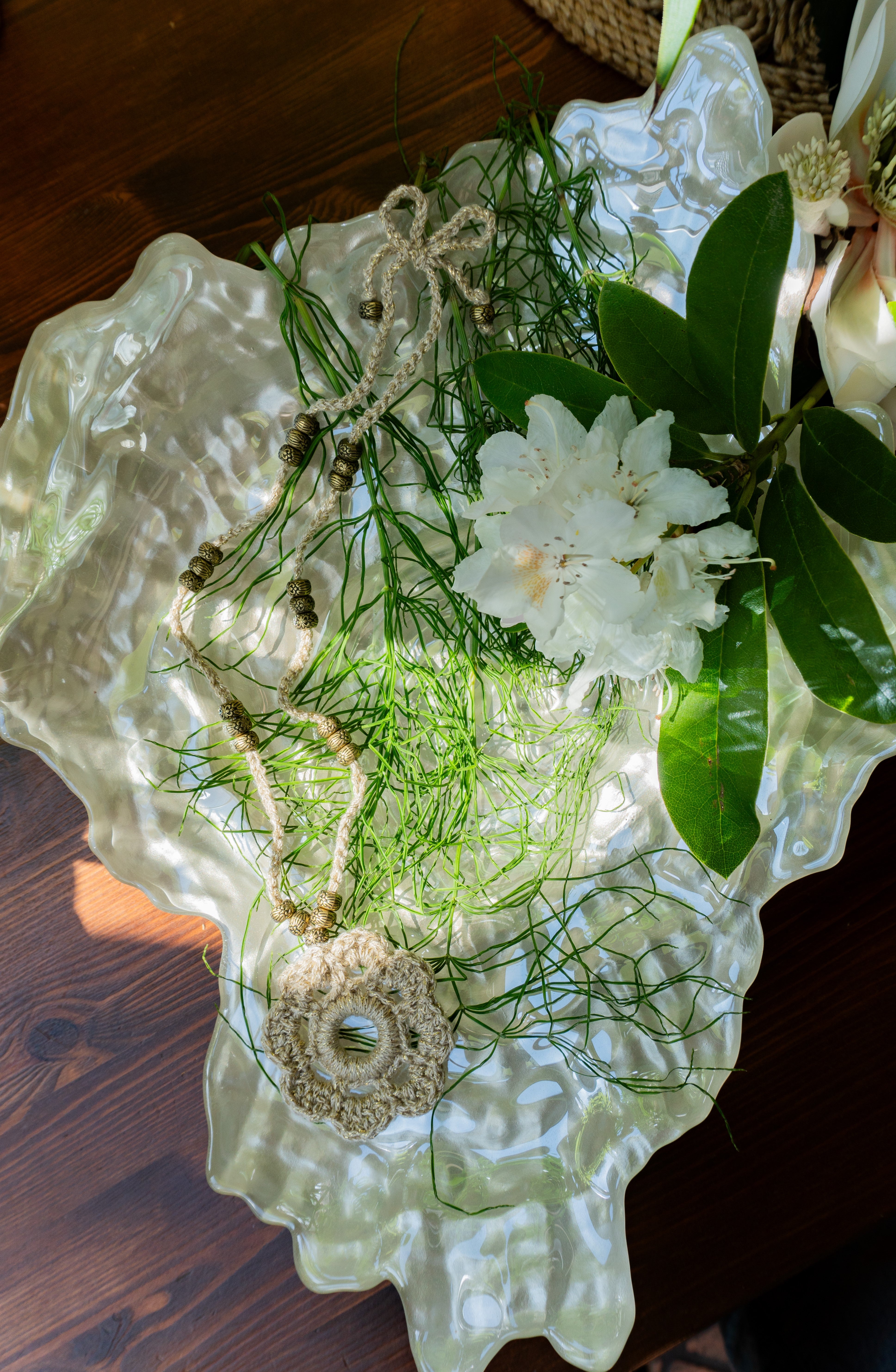 Verleihe deinem Boho Look einen Hauch von Eleganz mit unserer handgefertigten Häkelkette. Das Unikat besteht aus edlem metallic-gold Effektgarn und ist mit einem Häkel-Blumen Anhänger sowie passenden Ethno Style Perlen versehen. Perfekt als sommerliches Accessoire.