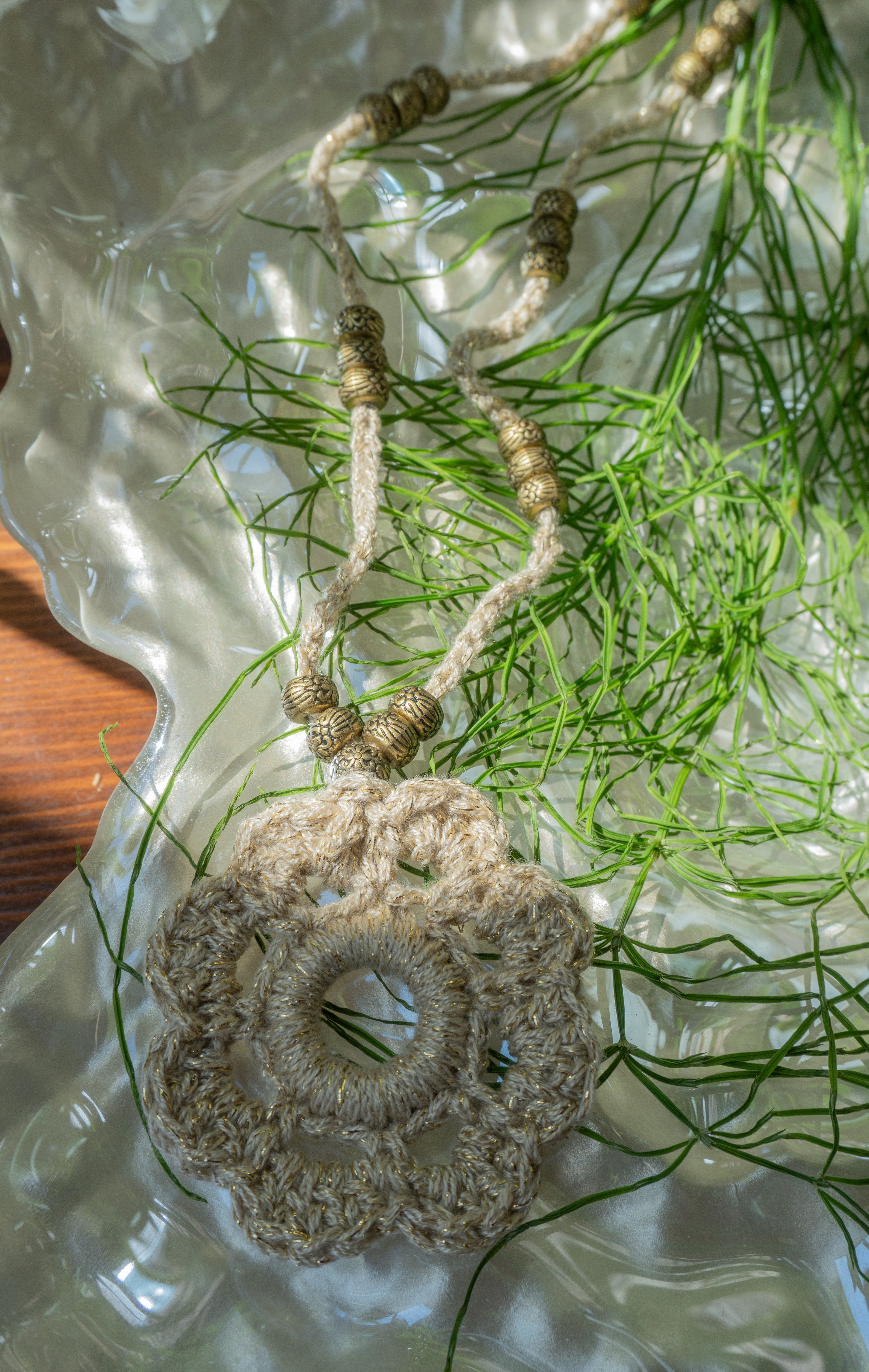 Verleihe deinem Boho Look einen Hauch von Eleganz mit unserer handgefertigten Häkelkette. Das Unikat besteht aus edlem metallic-gold Effektgarn und ist mit einem Häkel-Blumen Anhänger sowie passenden Ethno Style Perlen versehen. Perfekt als sommerliches Accessoire.