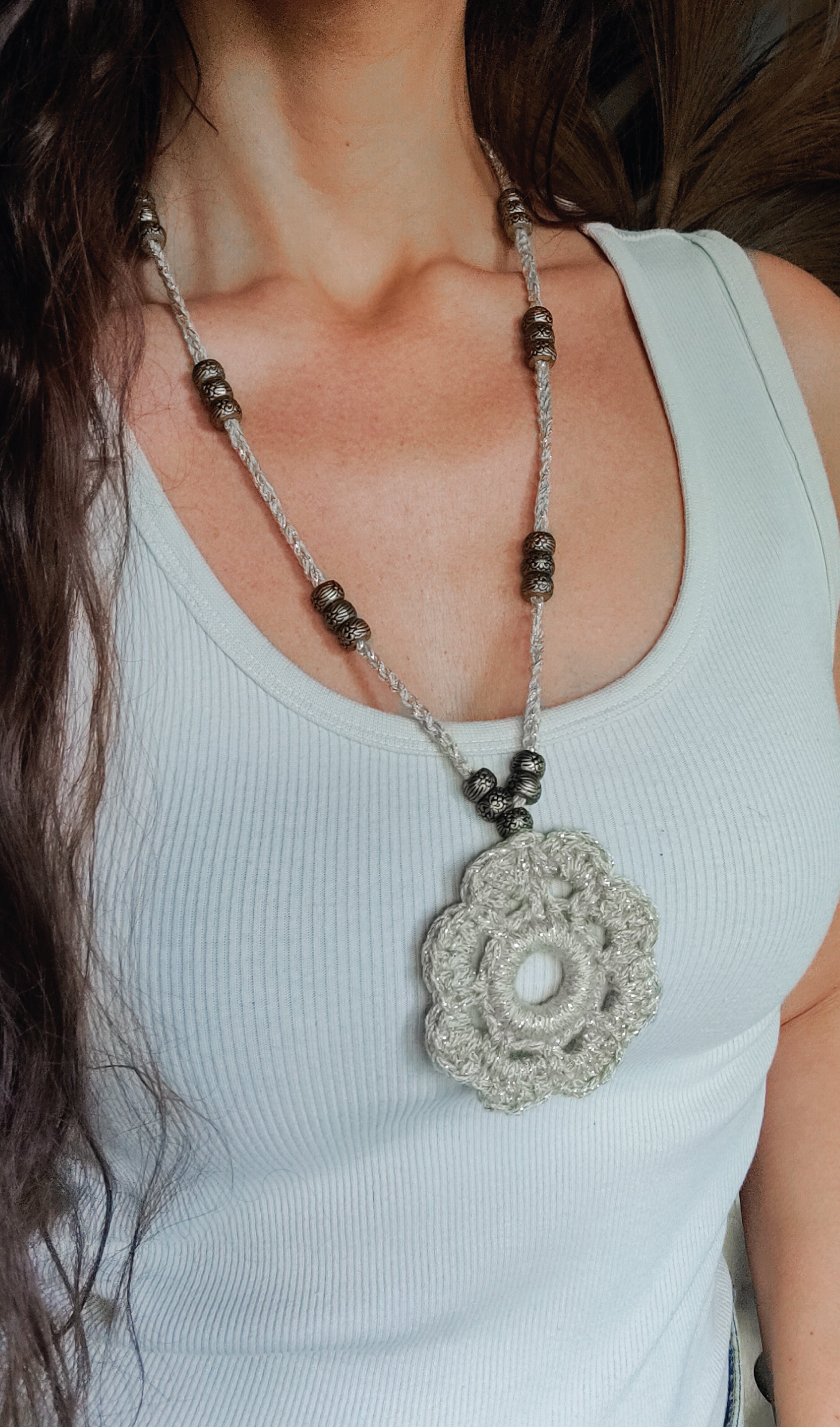 Verleihe deinem Boho Look einen Hauch von Eleganz mit unserer handgefertigten Häkelkette. Das Unikat besteht aus edlem metallic-gold Effektgarn und ist mit einem Häkel-Blumen Anhänger sowie passenden Ethno Style Perlen versehen. Perfekt als sommerliches Accessoire.