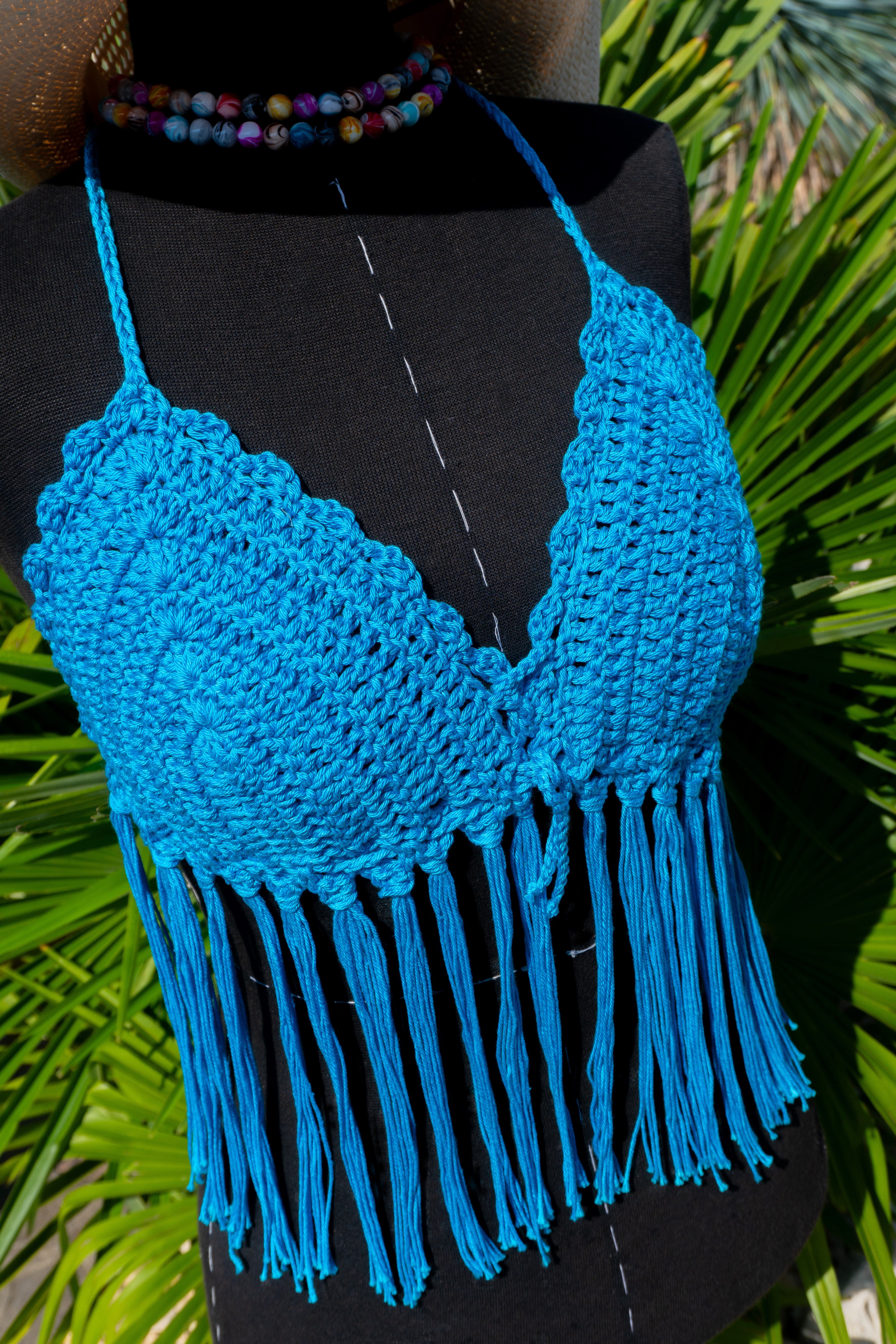 Handgefertigtes Häkeltop in leuchtendem Türkis mit Fransen ist der ideale Begleiter für Festivals, Strandtage und den Sommer! Die verstellbaren Bänder am Nacken und Rücken sorgen für bequemen Tragekomfort. Aus hochwertiger merzerisierter Baumwolle.