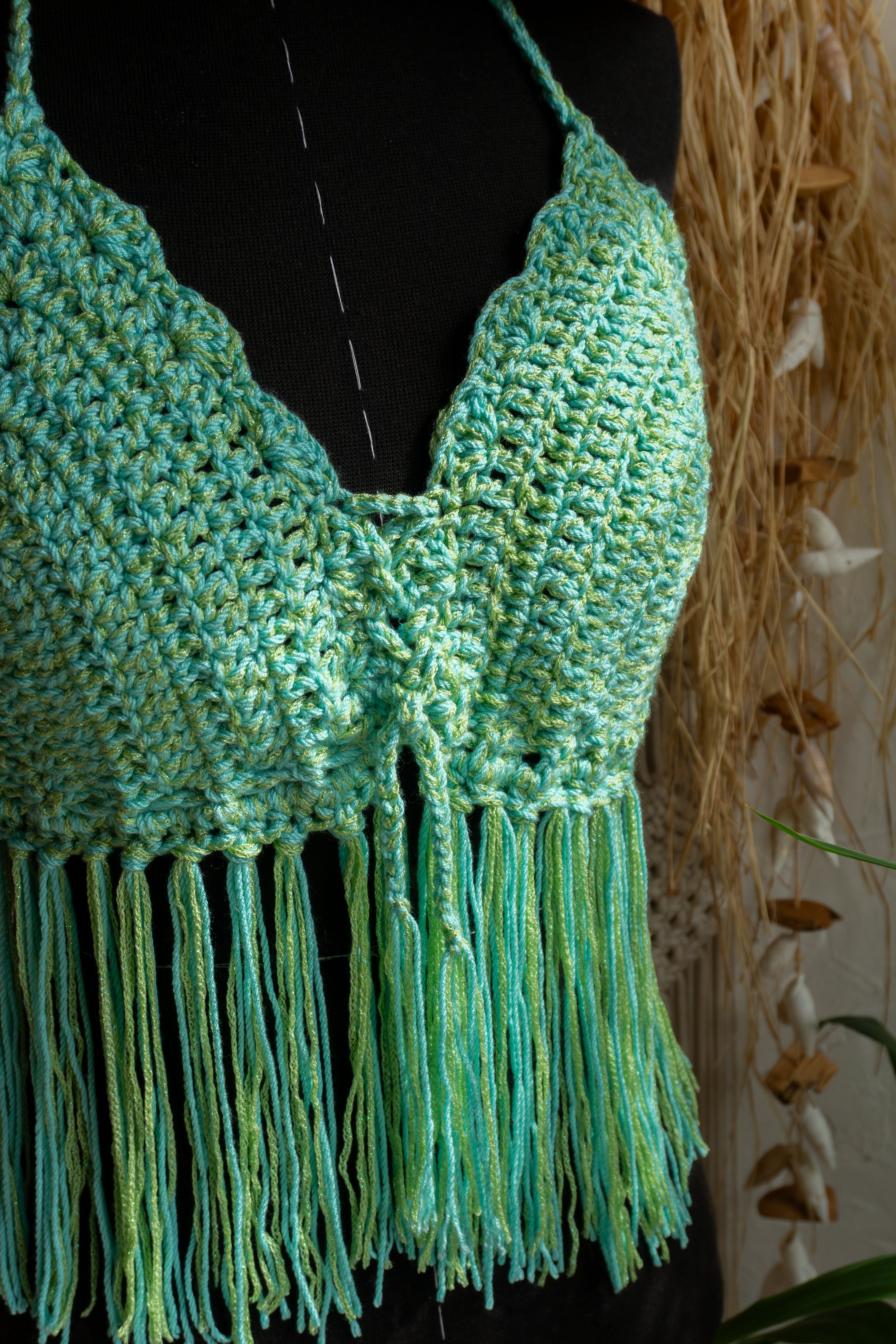 Handgefertigtes Häkeltop in Grün-Mint. Die Fransen und der Kantenabschluss verleihen dem Top einen verspielten Look. Das weiche Garn mit Metallic-Effekt fühlt sich nicht nur angenehm auf der Haut an, sondern verleiht auch einen edlen Touch. Verstellbar im Nacken, am Rücken und am Ausschnitt für optimalen Tragekomfort.