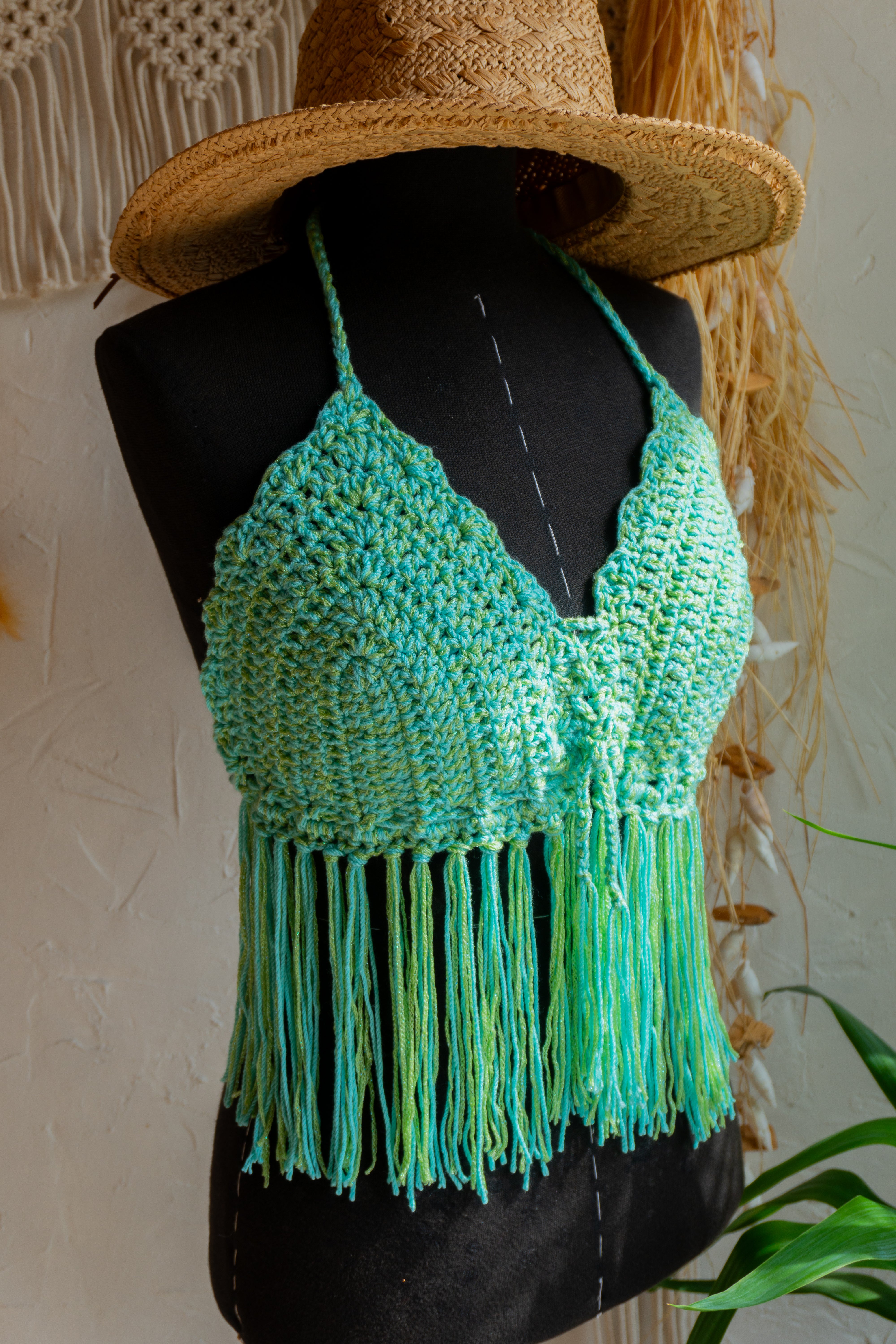 Handgefertigtes Häkeltop in Grün-Mint. Die Fransen und der Kantenabschluss verleihen dem Top einen verspielten Look. Das weiche Garn mit Metallic-Effekt fühlt sich nicht nur angenehm auf der Haut an, sondern verleiht auch einen edlen Touch. Verstellbar im Nacken, am Rücken und am Ausschnitt für optimalen Tragekomfort.