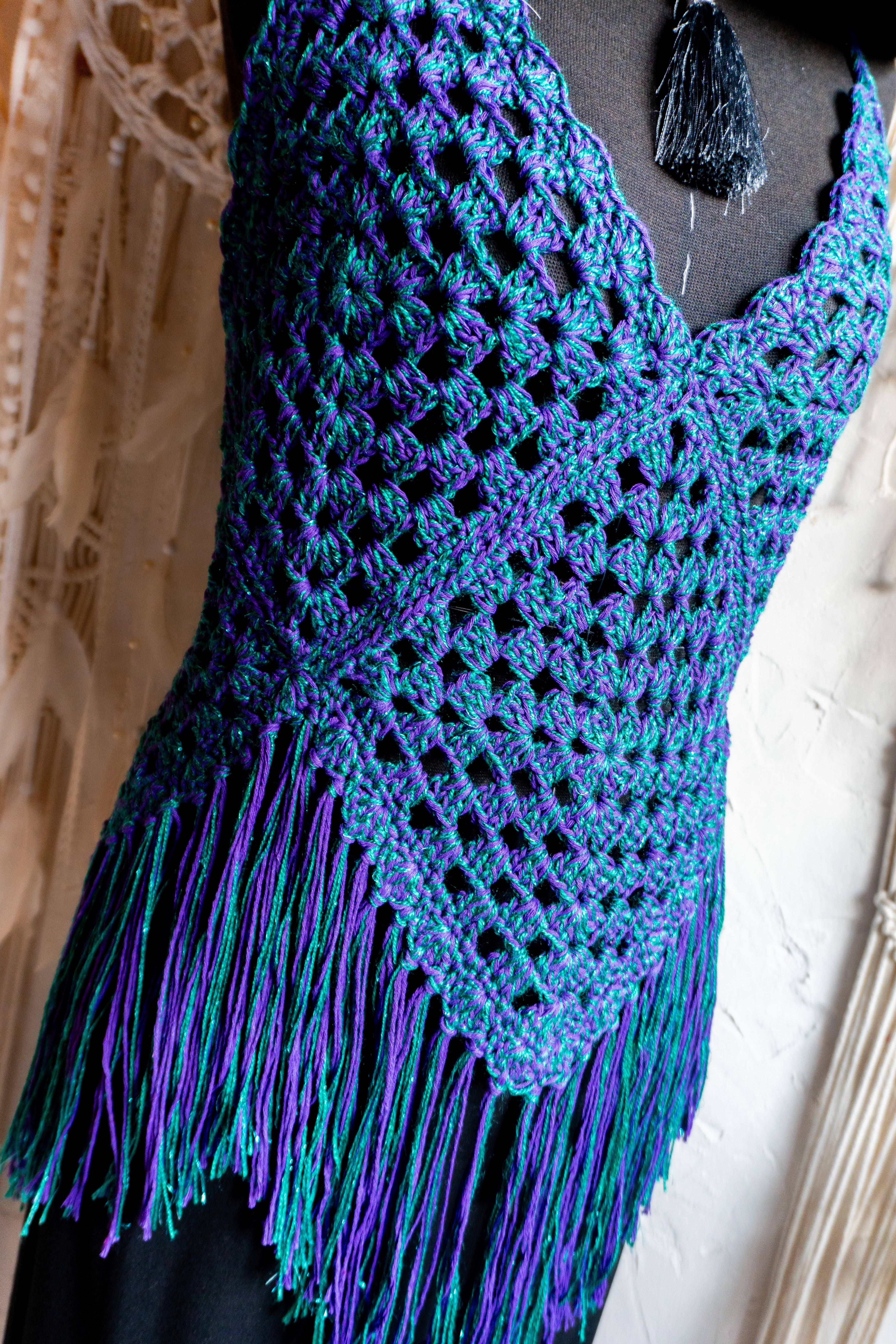 Handgefertigtes Unikat Häkeltop in einem auffälligen Farbmix aus Lila-Grün Metallic - ein stylisher Hingucker! Perfekt für ein stylisches Boho-inspiriertes Outfit. Individuell anpassbare Neckholder-Träger und Rückenbänder sorgen für perfekten Sitz und ein angenehmes Hautgefühl. Die stylischen Fransen verleihen dem Top eine lässige Note und machen es zum absoluten Must-have. Kombiniere es nach Bedarf mit einem passenden Bikini Oberteil darunter. Mit Liebe in Deutschland handgefertigt.