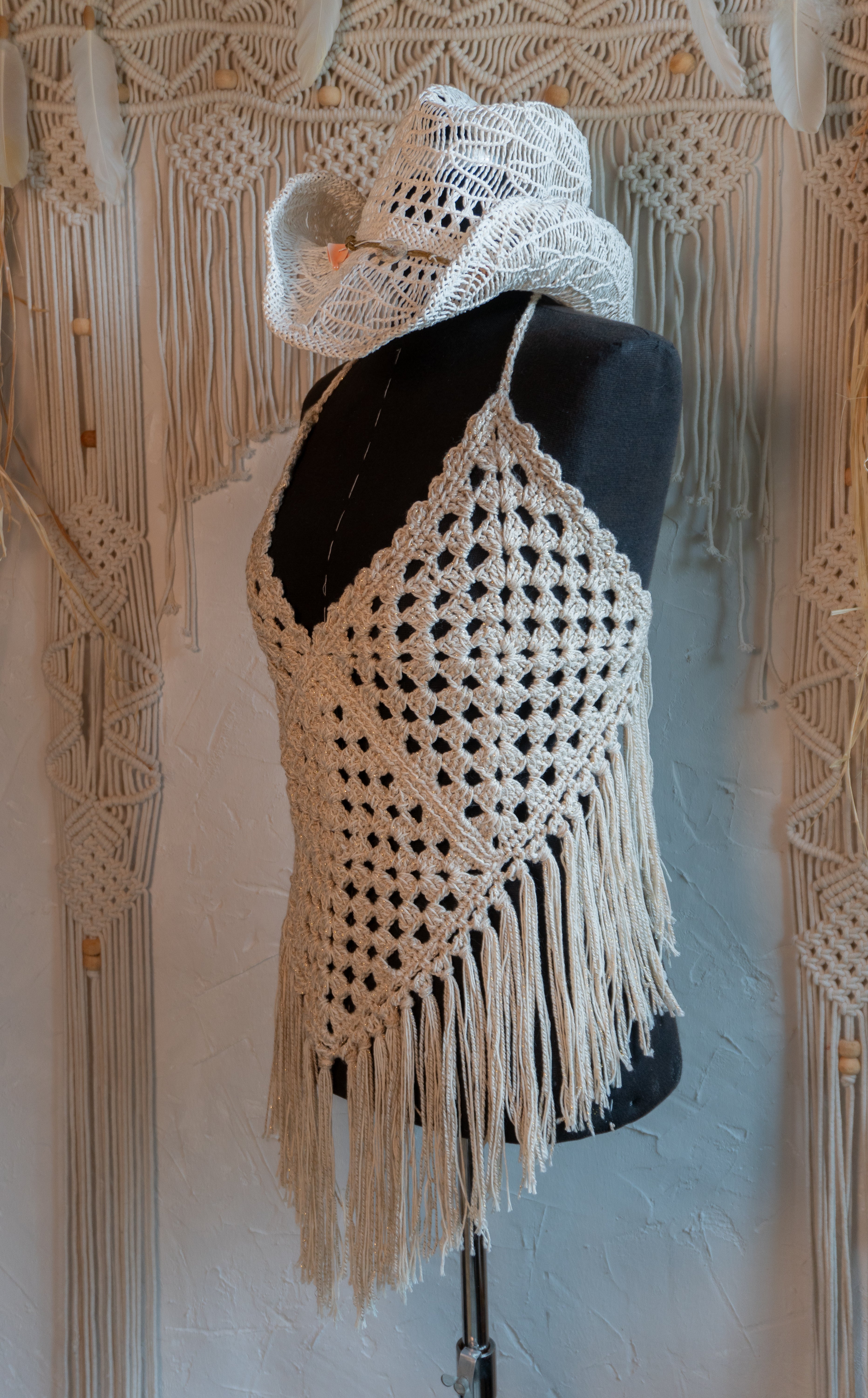 Das handgefertigte Häkeltop in Beige-Gold ist perfekt für den Hippe Boho Style und besticht durch den Mix mit edlem Metalliceffekt-Garn. Mit individuell verstellbaren Trägern im Nacken und am Rücken passt es sich jeder Figur an und sorgt für ein bequemes Tragegefühl. Ideal für Festivals, Strandbesuche oder den sommerlichen Look.