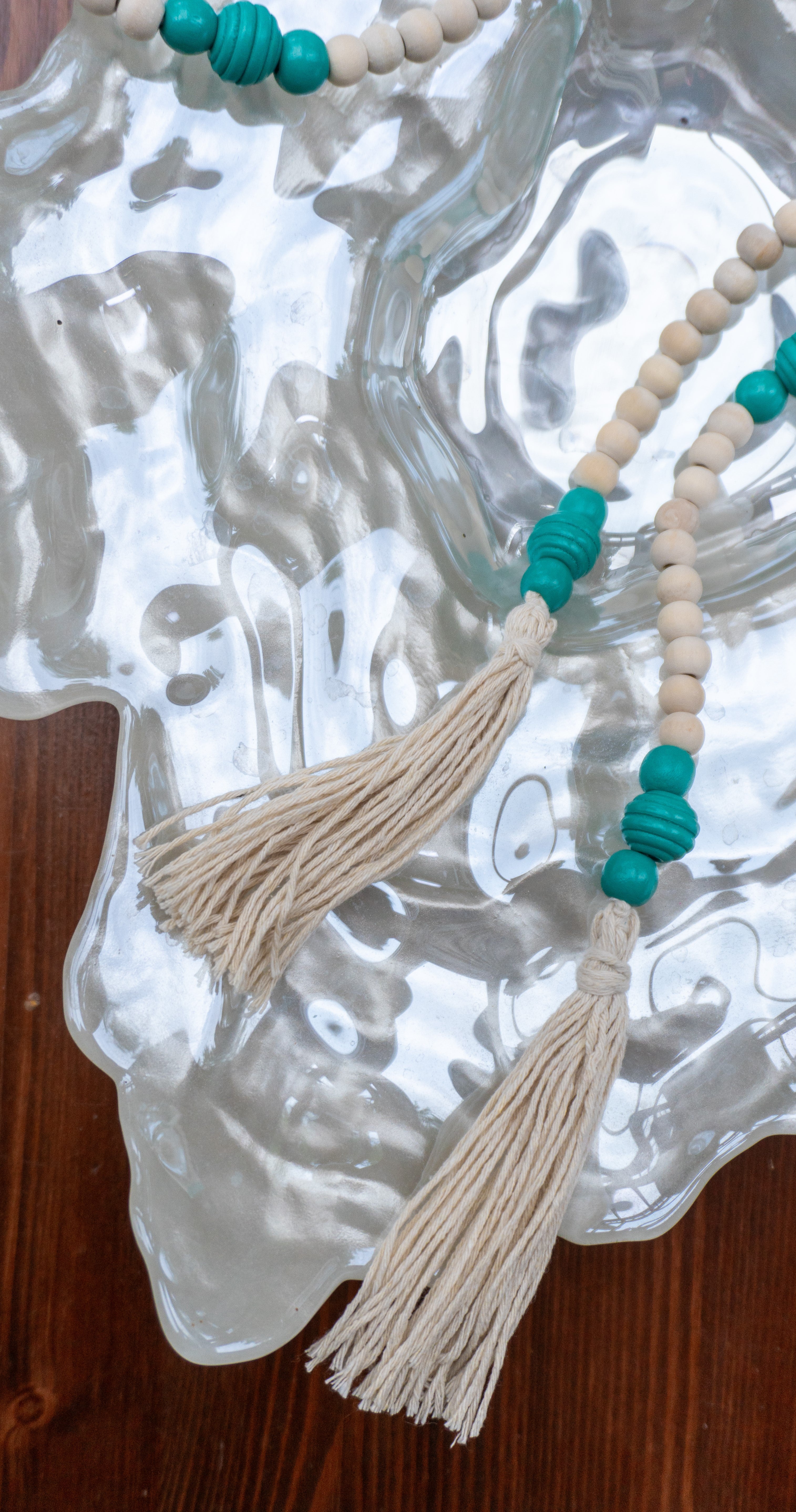 Diese handgefertigte, vielseitig einsetzbare Holzperlen Deko Kette in Mint-Beige mit Tasseln bringt den angesagten Boho Stil in dein Zuhause. Schmücke deinen Blumentopf, dekoriere deinen Tisch oder nutze sie als Deko-Element - die Möglichkeiten sind vielseitig.