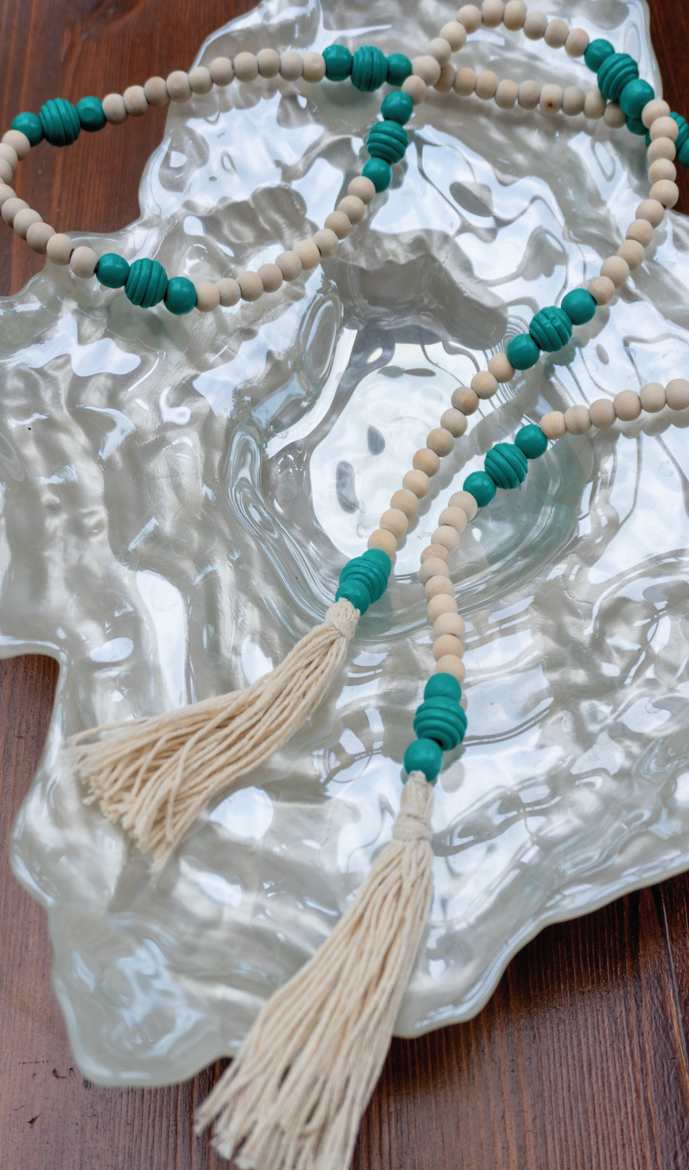 Diese handgefertigte, vielseitig einsetzbare Holzperlen Deko Kette in Mint-Beige mit Tasseln bringt den angesagten Boho Stil in dein Zuhause. Schmücke deinen Blumentopf, dekoriere deinen Tisch oder nutze sie als Deko-Element - die Möglichkeiten sind vielseitig.