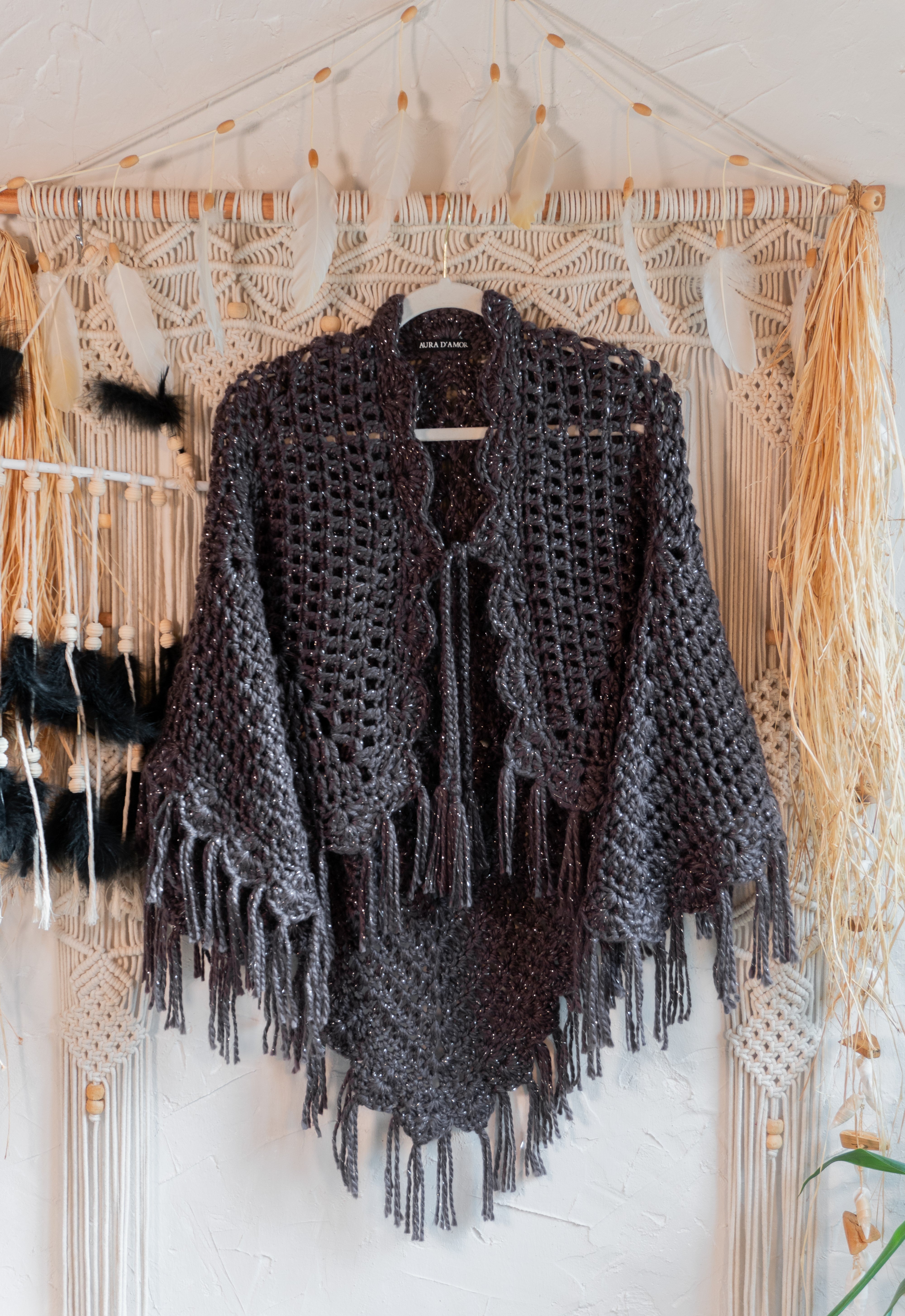 Verleihe deinem Herbst- oder Übergangsoutfit mit dieser absolut exklusiven Einzelstück Häkel Poncho-Jacke in edlem Anthrazit-Metallic und mit schönen Fransen den besonderen Boho-Chic Touch. Die Bänder am Ausschnitt sorgen nicht nur für eine tolle Optik, sondern auch für einen bequemen Sitz. Ein Must-Have für alle, die sich gerne von der Masse abheben wollen!