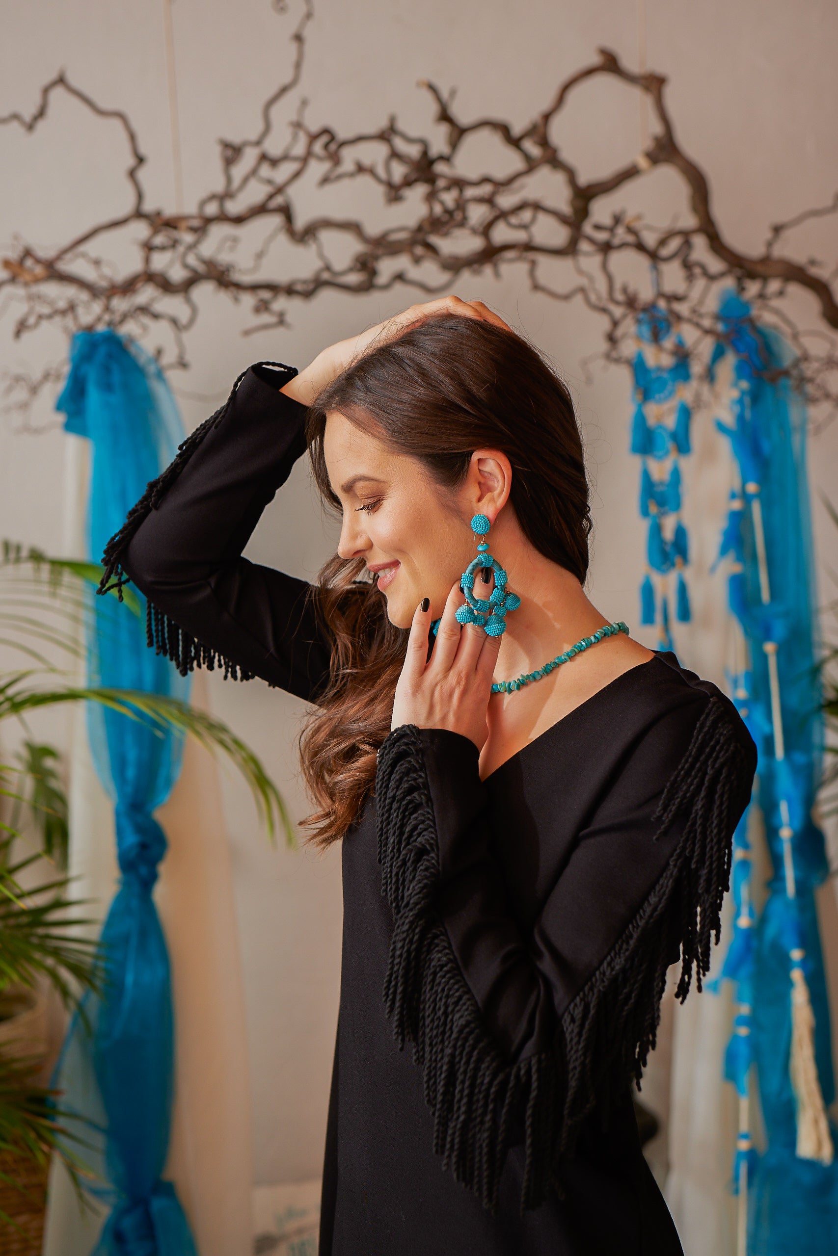Dieses lange, schwarze Boho-Stretchkleid überzeugt mit gedrehten Fransen an den Ärmeln und einem eleganten V-Ausschnitt. Schulterpolster und seitliche Schlitze verleihen dem Kleid eine moderne Silhouette. Das blickdichte, formbeständige Stretchmaterial sorgt für hohen Tragekomfort und eine entspannte Passform. Vielseitig kombinierbar, lässt es sich mit einem Gürtel individuell stylen – ideal für einen lässigen Bohemian Look. Das streng limitierte Design macht es zu einem besonderen Highlight