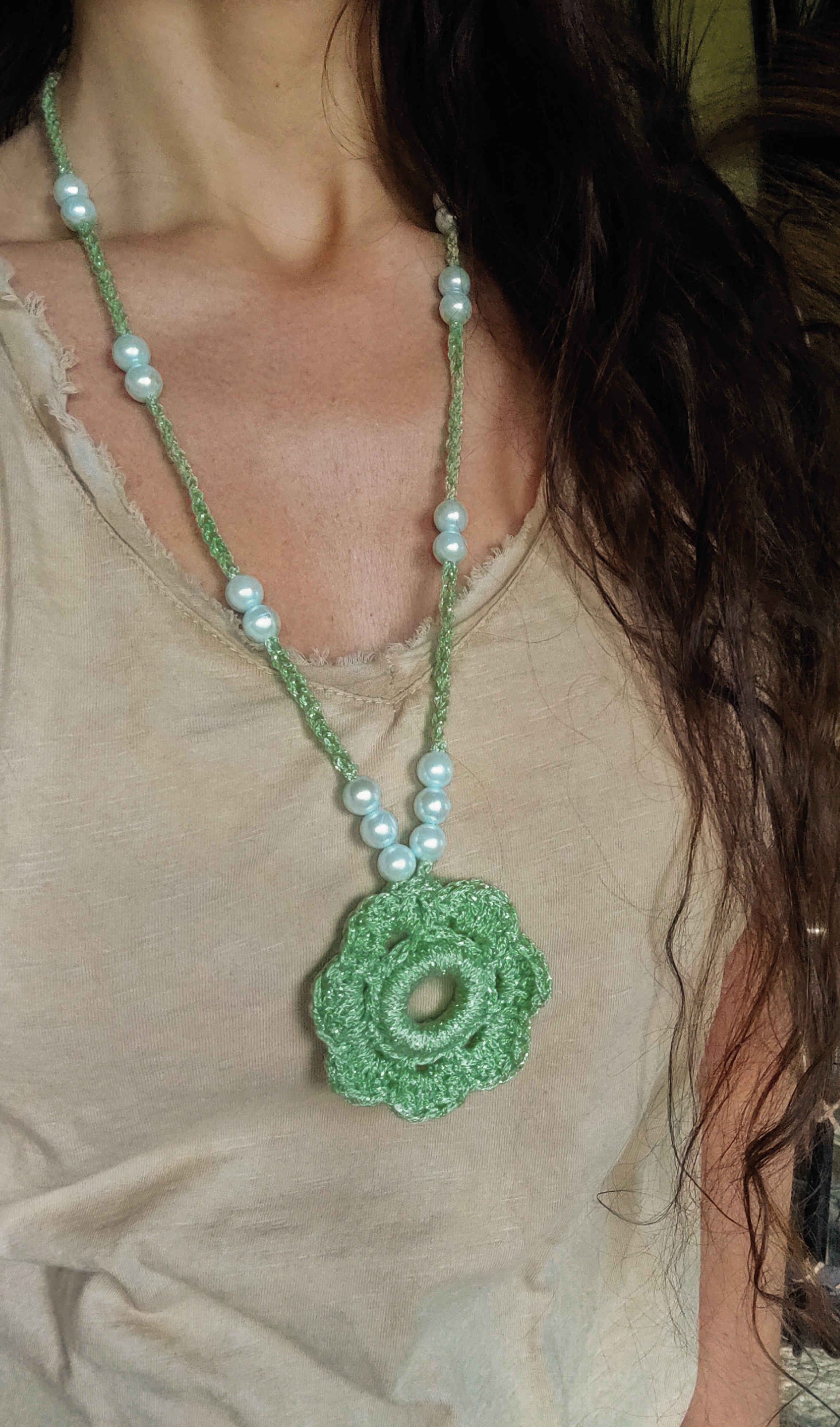 Erstrahle diesen Sommer mit unserer einzigartigen handgefertigten Häkelkette in pastell Metallic grün. Der Blumen Optik Anhänger und die passenden Perlen verleihen dir den perfekten Boho Sommer Look. Genieße die warmen Sonnenstrahlen und sei der Hingucker auf jedem Event. Die Kette ist aus metalliceffekt Garn, das für einen besonderen Glanz sorgt.
